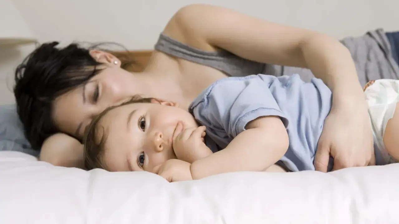 Mama tuli roczne dziecko do snu, przytulając je blisko.