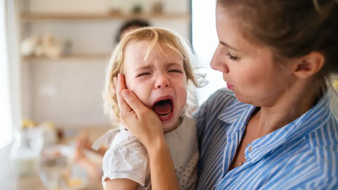 Mama próbuje uspokoić dziecko, które przeżywa histerię. Płacz malucha jest bardzo intensywny.