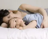Mama tuli roczne dziecko do snu, przytulając je blisko.