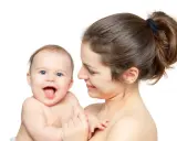 Uśmiechnięta mama tuli radosne dziecko. Pomimo nerwowa atmosfera w domu, dziecko rozjaśnia wszystko swoim uśmiechem.