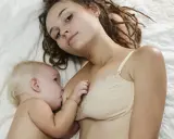 Mama z dredami karmi piersią niemowlę. To piękny moment bliskości, choć nie jest to karmienie piersią 10 latka.