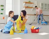 Mama i córka świętują udane porządki. W tle tata odkurza. To świetny przykład, jak obowiązki 9 latka w domu mogą być wspólną zabawą.