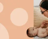 Mama z okularami delikatnie podnosi nóżki dziecka, przygotowując się do zakładania pampersa na stojąco.