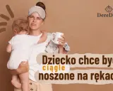 Zmęczona mama z opaską na oczach trzyma płaczące roczne dziecko, które ciągle chce na ręce. Obok kubek i stosik ubranek.