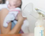 Laktator z butelką mleka, w tle mama z dzieckiem. Zastanawiasz się, ile trwa nawał mleczny?