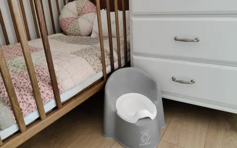 Szara nocniczka BabyBjörn obok łóżeczka. Czas na rozwiązanie problemu z odpieluchowaniem 3 latka.