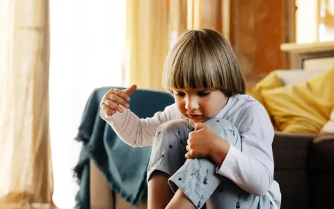 Chłopiec w piżamie z gitarami, zamyślony, jakby przeżywał tiki u dzieci w wieku szkolnym.