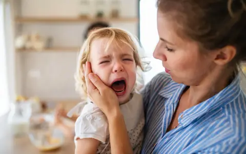Mama próbuje uspokoić dziecko, które przeżywa histerię. Płacz malucha jest bardzo intensywny.
