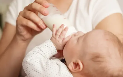 Dziecko pije mleko modyfikowane z butelki. Karmienie to może mieć różne konsekwencje dla rozwoju malucha.