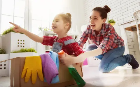 Mama i dziecko bawią się w sprzątanie, ucząc się jak nauczyć dziecko sprzątać. W kartonie są rękawice i płyn.