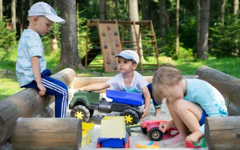 Dzieci bawią się w piaskownicy, ucząc się, jak pomóc dziecku być lubianym przez zabawę i dzielenie się zabawkami.