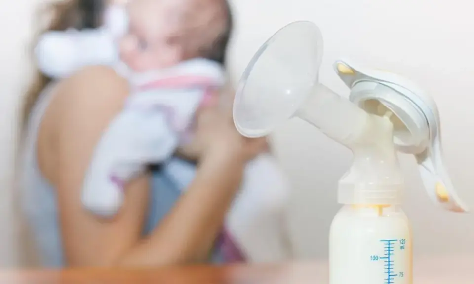 Laktator z butelką mleka, w tle mama z dzieckiem. Zastanawiasz się, ile trwa nawał mleczny?