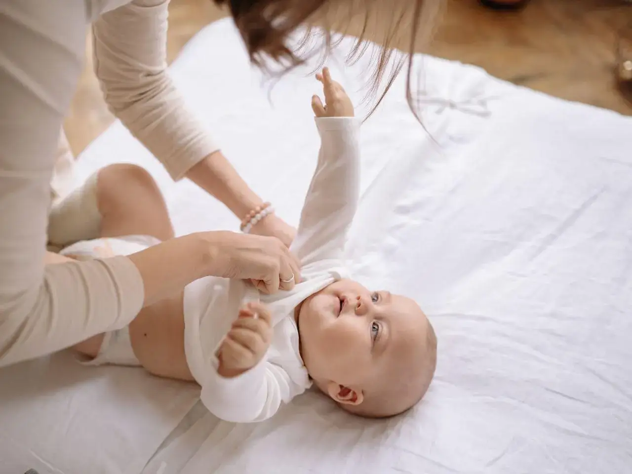 Mama ubiera dziecko na białym tle. Zastanawiasz się, przebodźcowanie niemowlaka ile trwa?