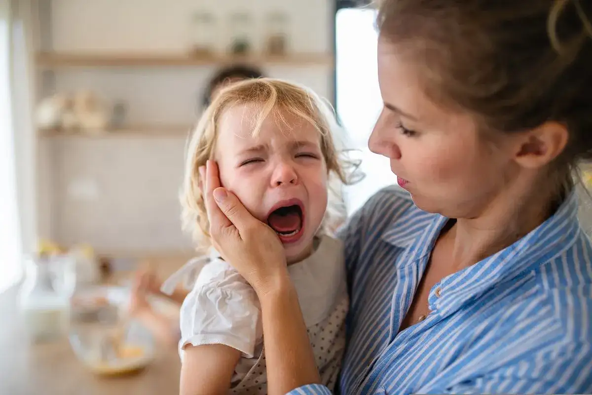 Mama pociesza płaczące dziecko, próbując uspokoić jego nerwowość.